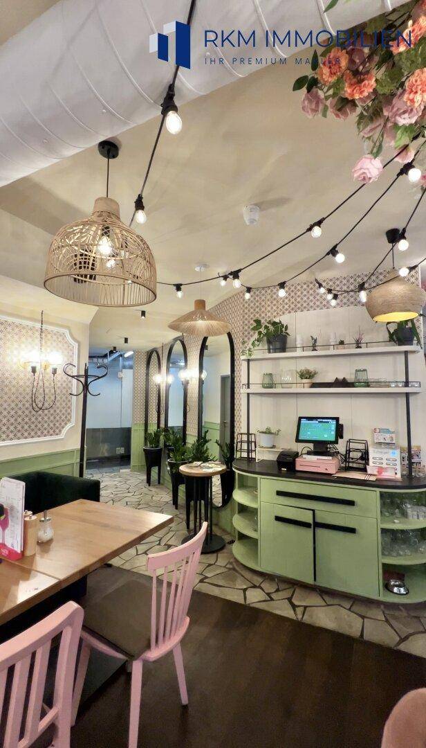 Servicebereich mit Theke und Sitzgelegenheiten in einem stilvollen Café mit floraler Dekoration.