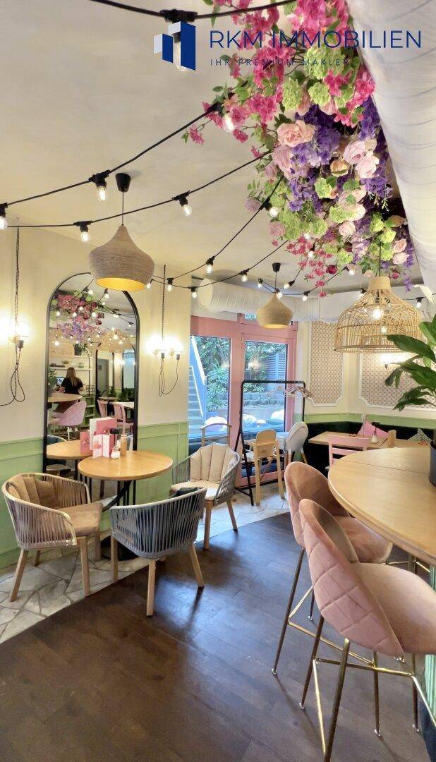 Heller Restaurantbereich mit unterschiedlichen Sitzmöglichkeiten, Spiegeln und floraler Deckendekoration.