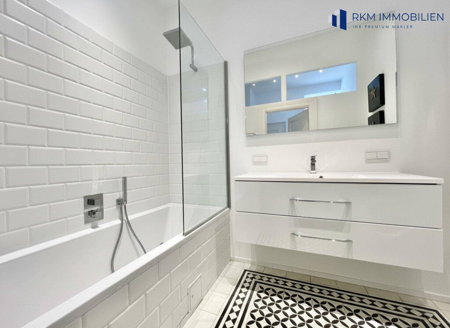 Modernes Badezimmer mit Badewanne, Dusche, Einzelwaschbecken und stilvollen weißen Fliesen.