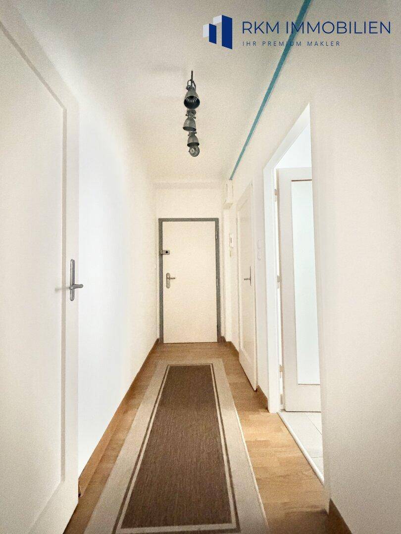 Heller Flur mit Holzboden und mehreren Türen, der zu verschiedenen Räumen führt.