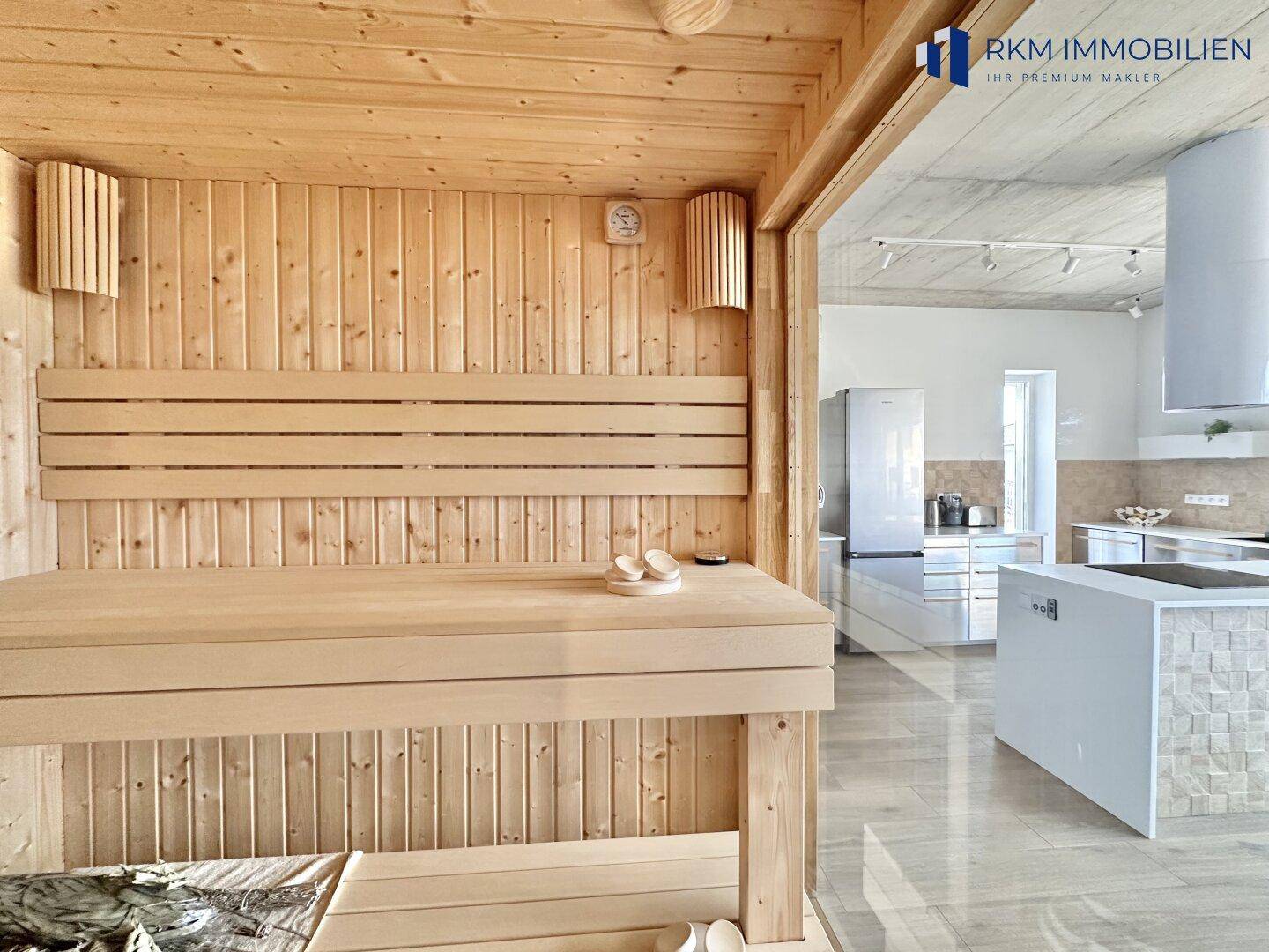 Gemütliche Holzsauna mit Blick auf den offenen Wohnbereich und die moderne Küche.