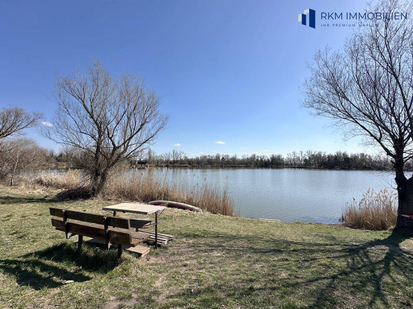 Malerischer Seeblick mit einer Bank und einem Tisch am Ufer, ideal zum Entspannen.