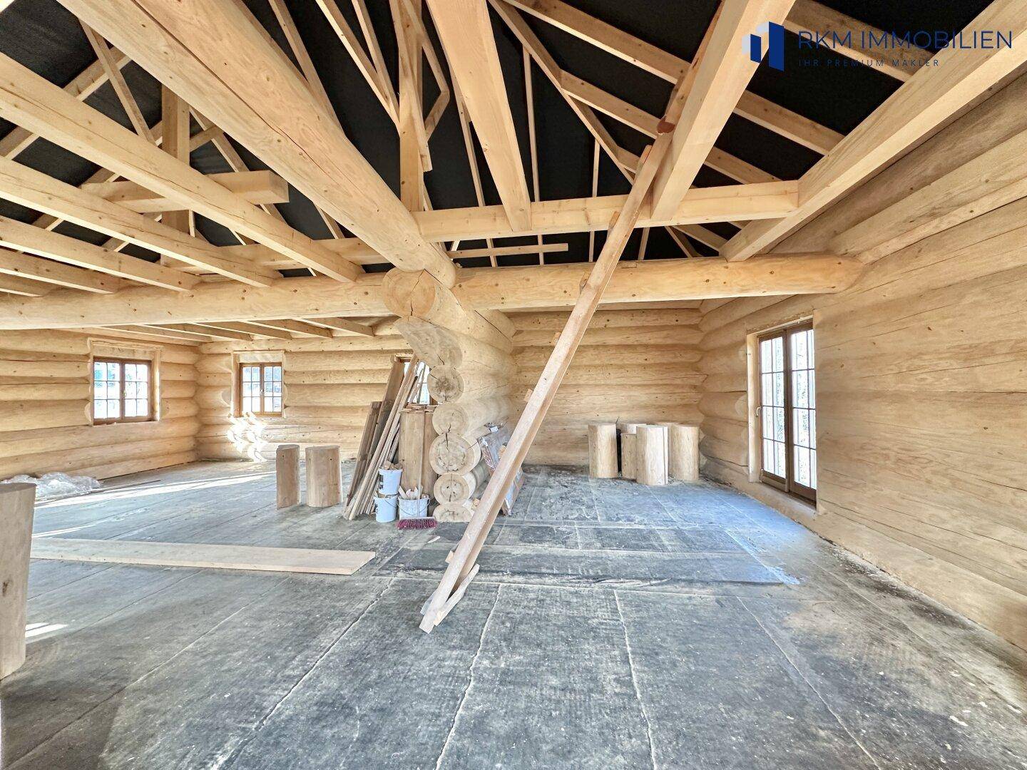 Blick in den unfertigen Innenraum des Blockhauses mit sichtbarer Holzkonstruktion und Rohfußboden.