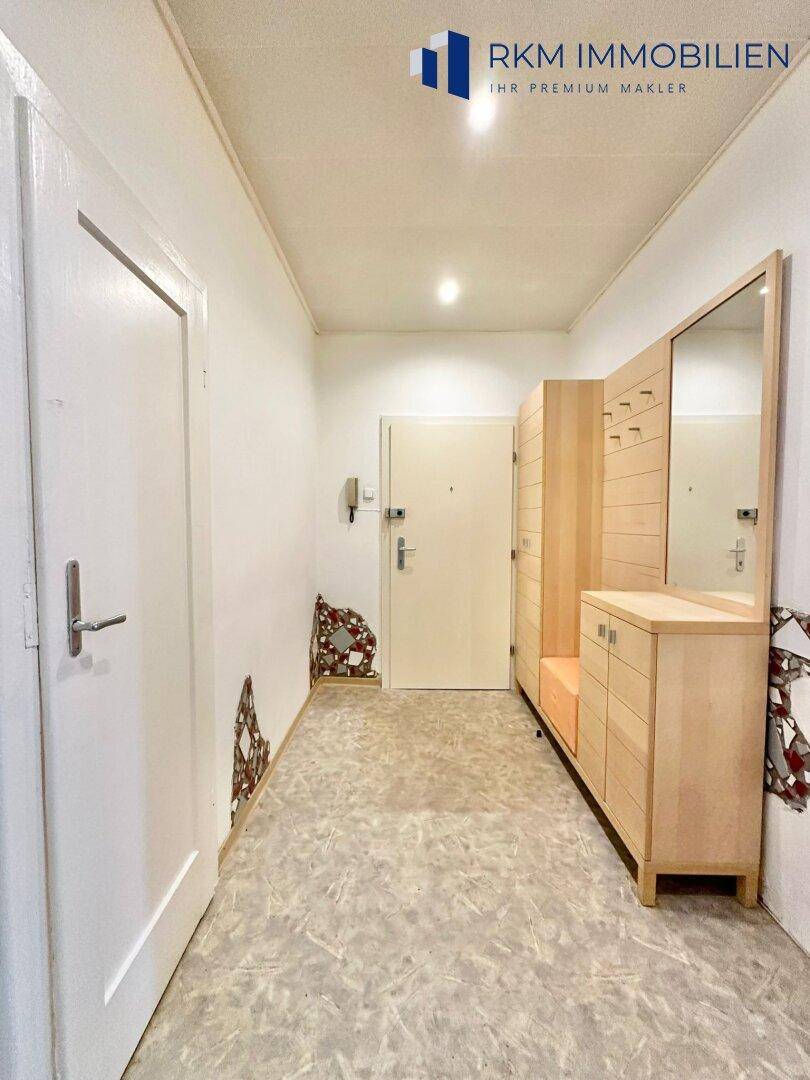 Heller Flur mit Garderobenmöbeln und Zugang zur Wohnungstür.