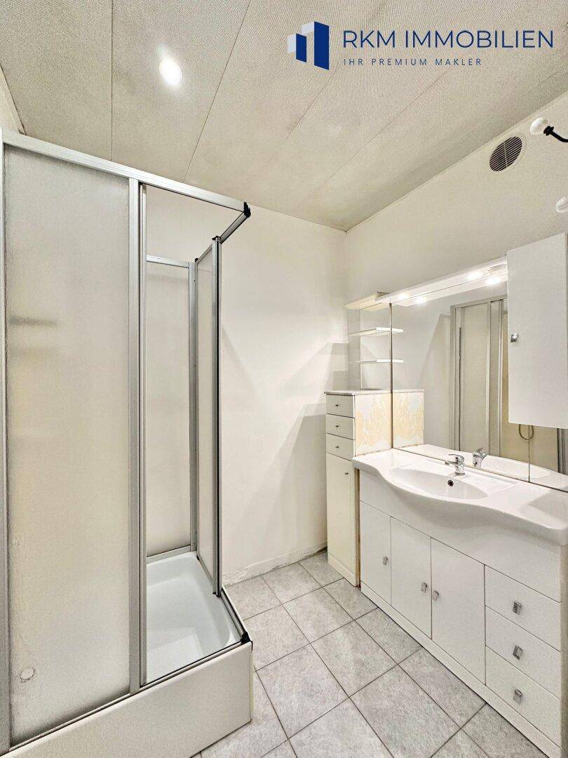 Badezimmer mit Duschkabine, Waschtisch und Spiegelschrank.