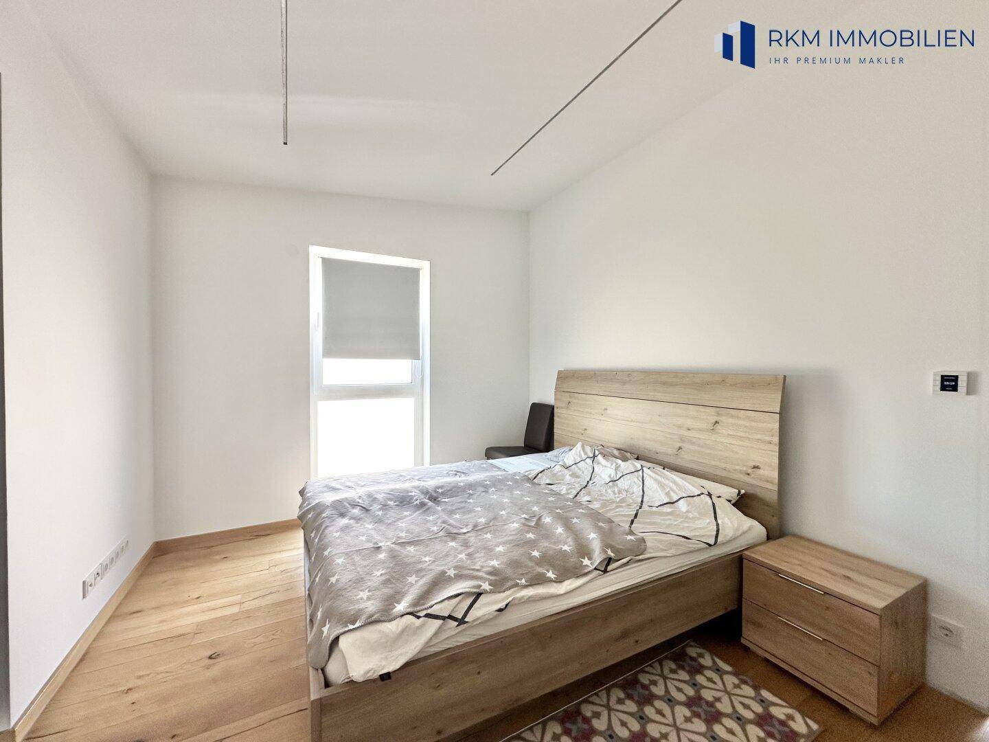 Gemütliches Schlafzimmer mit Holzboden, Doppelbett und einem großen Fenster.