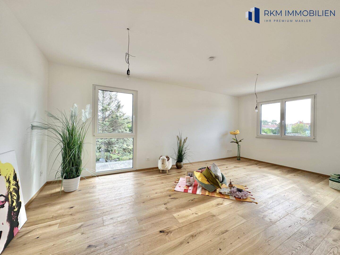 Geräumiges Zimmer mit hellem Holzboden und großen Fenstern, ideal als Schlaf- oder Kinderzimmer.