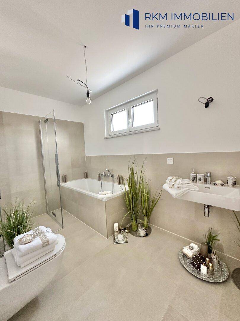 Modernes Badezimmer mit Badewanne, ebenerdiger Dusche, Wand-WC und Fenster.