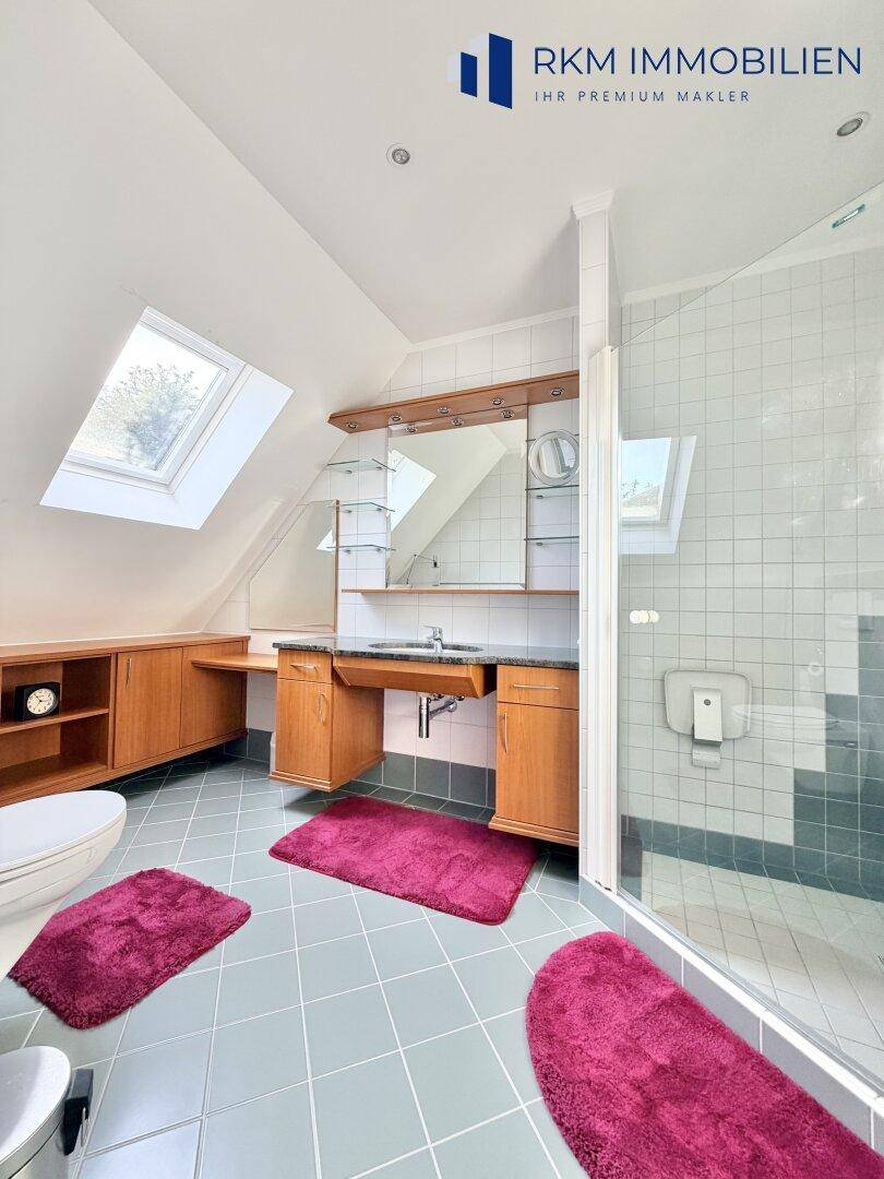 Modernes Badezimmer im Dachgeschoss mit Dusche, Waschtisch und Dachfenstern für viel Licht.