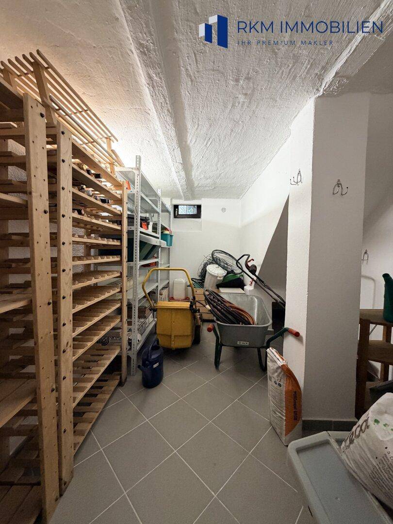 Geräumiger Kellerraum mit Weinregalen und zusätzlichem Stauraum für Gartengeräte.
