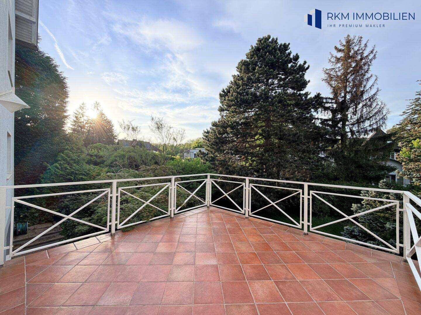 Große geflieste Terrasse mit weißem Geländer, ideal für Entspannung und Sonnenbaden.