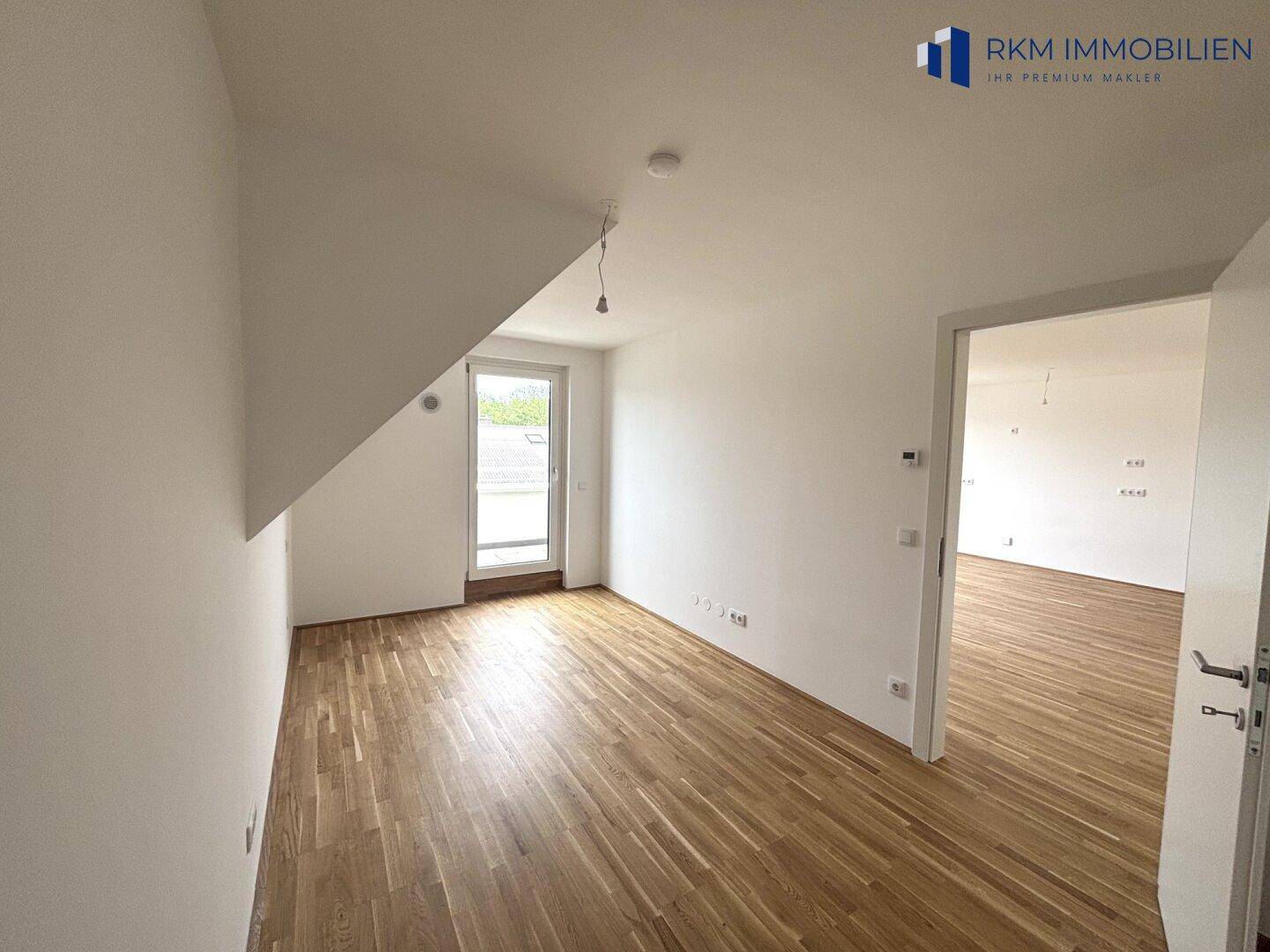 Helles Zimmer mit Parkettboden und Zugang zu einem Balkon, ideal als Schlaf- oder Arbeitszimmer.