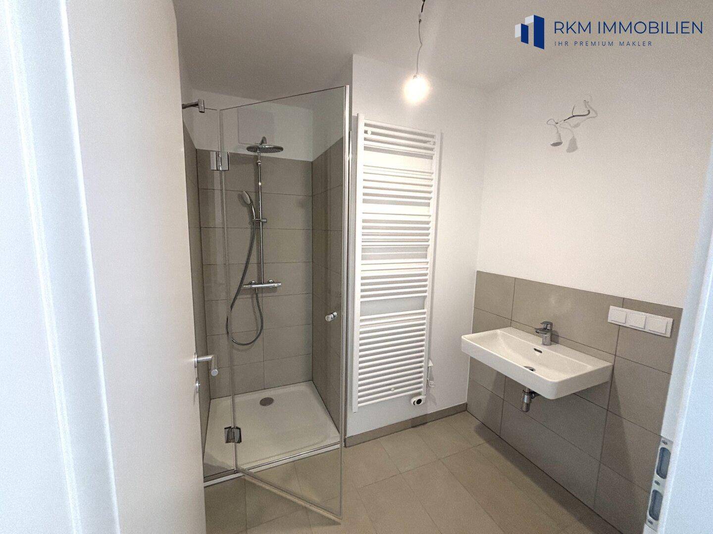 Modernes Badezimmer mit begehbarer Dusche, Wandfliesen und beheiztem Handtuchhalter.