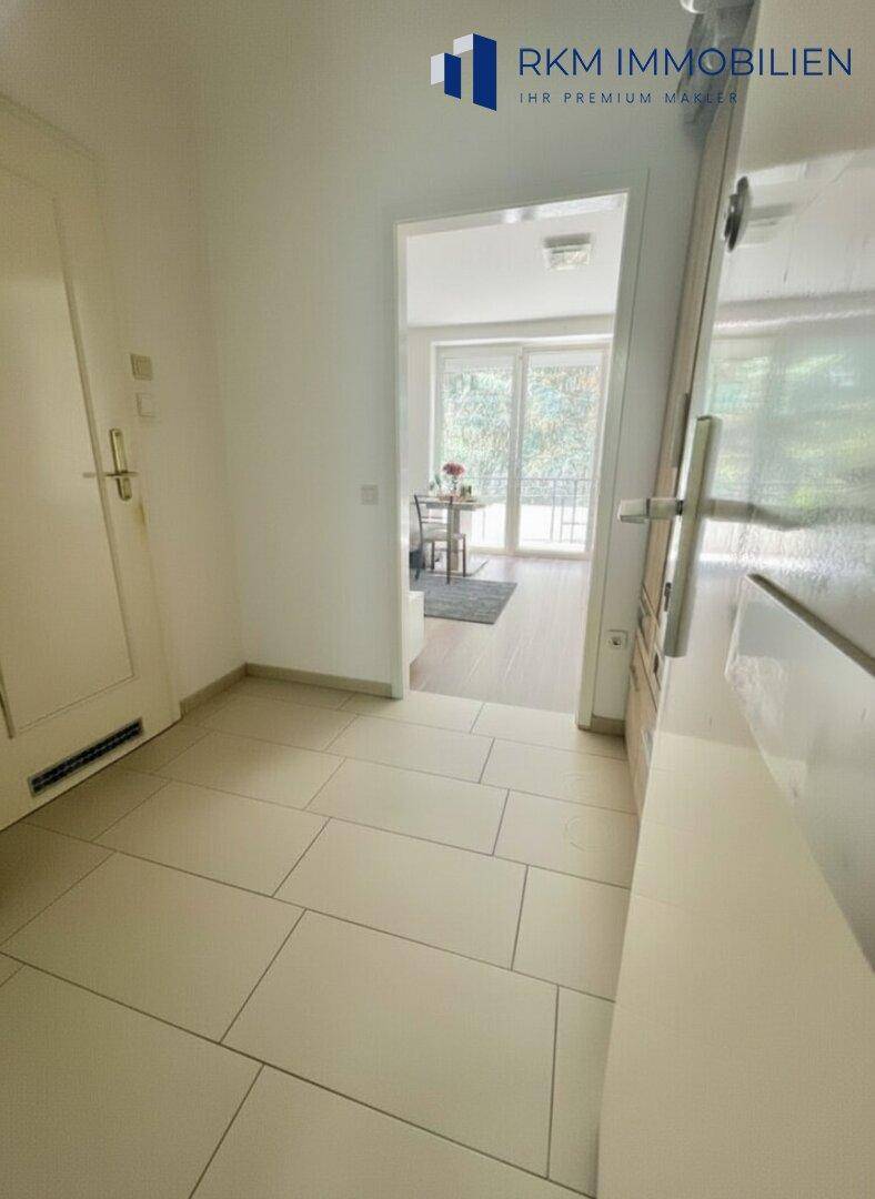 Gefliester Flur mit Zugang zu weiteren Räumen und Blick auf einen Balkon.