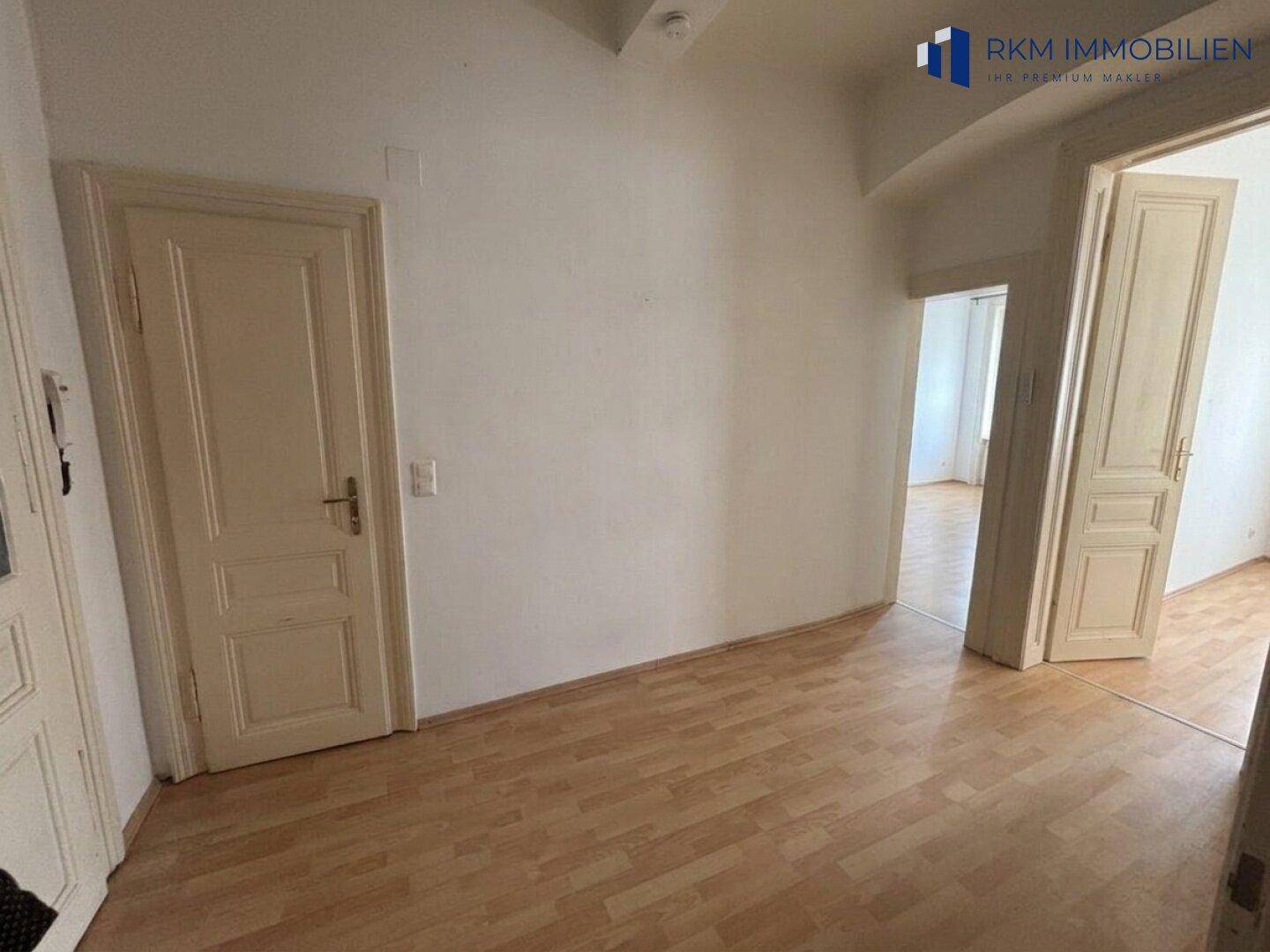 Heller Flur mit Laminatboden und klassischen Holztüren, der zu weiteren Räumen führt.