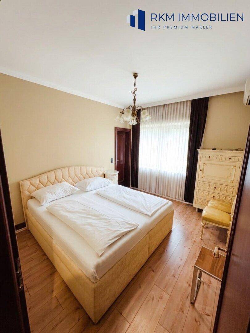 Helles Schlafzimmer mit Doppelbett, Holzfußboden und Klimaanlage für angenehme Temperaturen.
