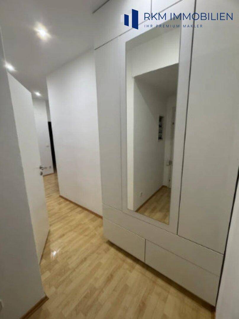 Heller Flur mit Parkettboden und einem großen Spiegelschrank, der den Raum erweitert.