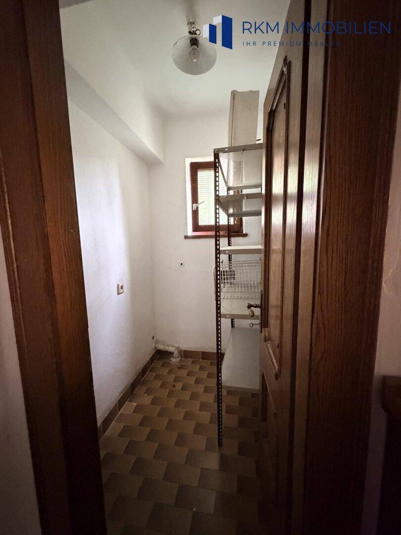 Kleiner Abstellraum mit Fliesenboden, Regal und einem Fenster.