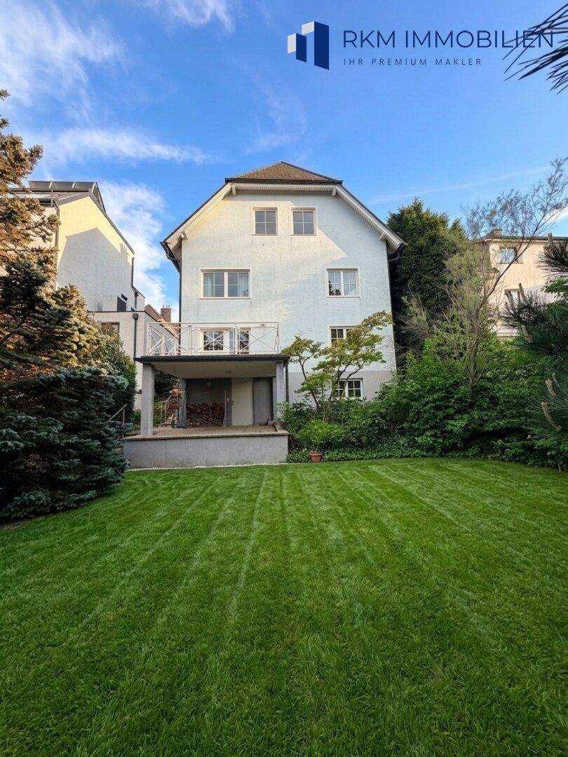 Hinteransicht des Hauses mit großem, gepflegtem Rasen und einer überdachten Terrasse im Erdgeschoss.
