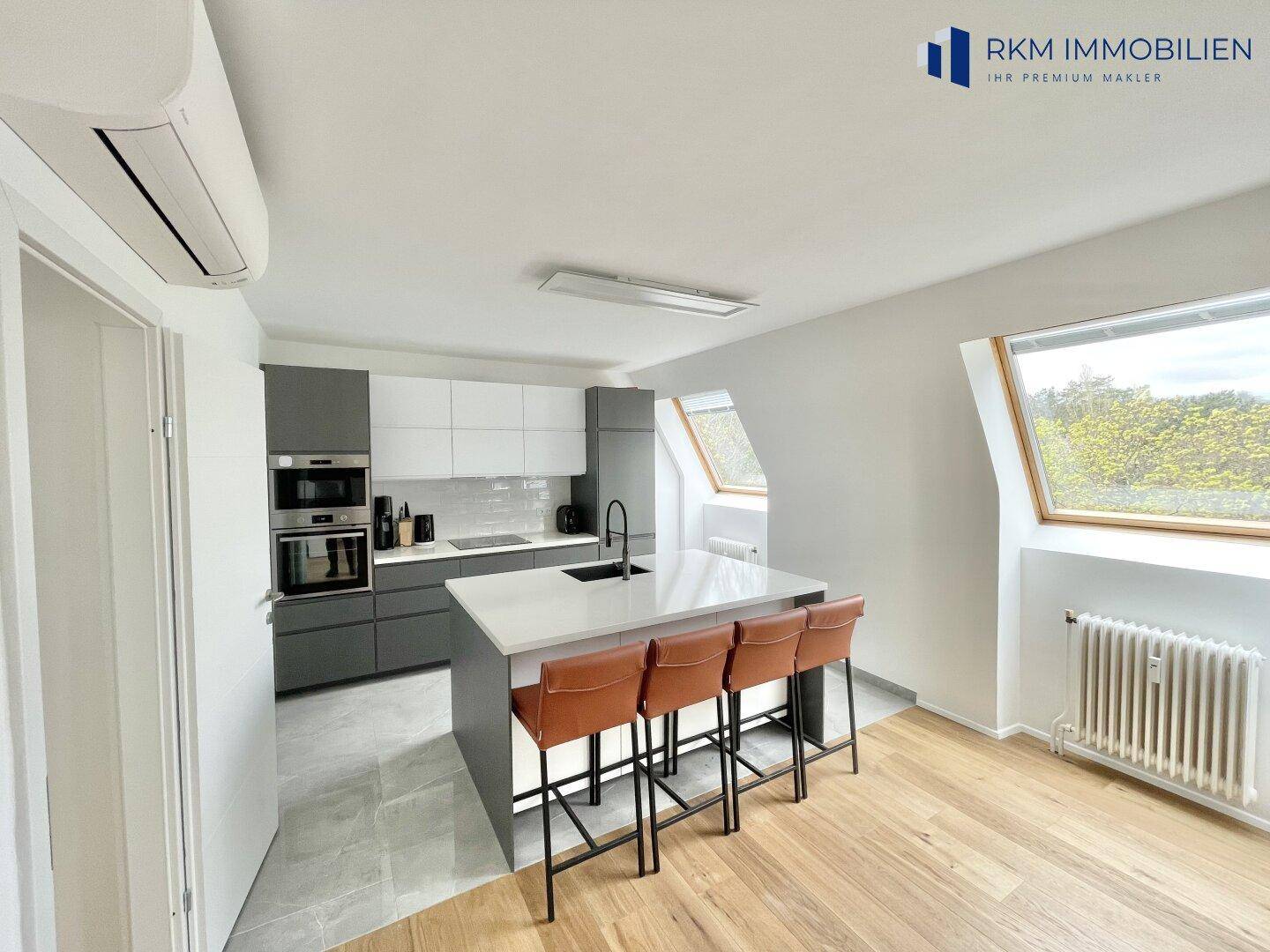 Moderne Küche mit grauen und weißen Schränken, Kücheninsel und Holzboden im Dachgeschoss.