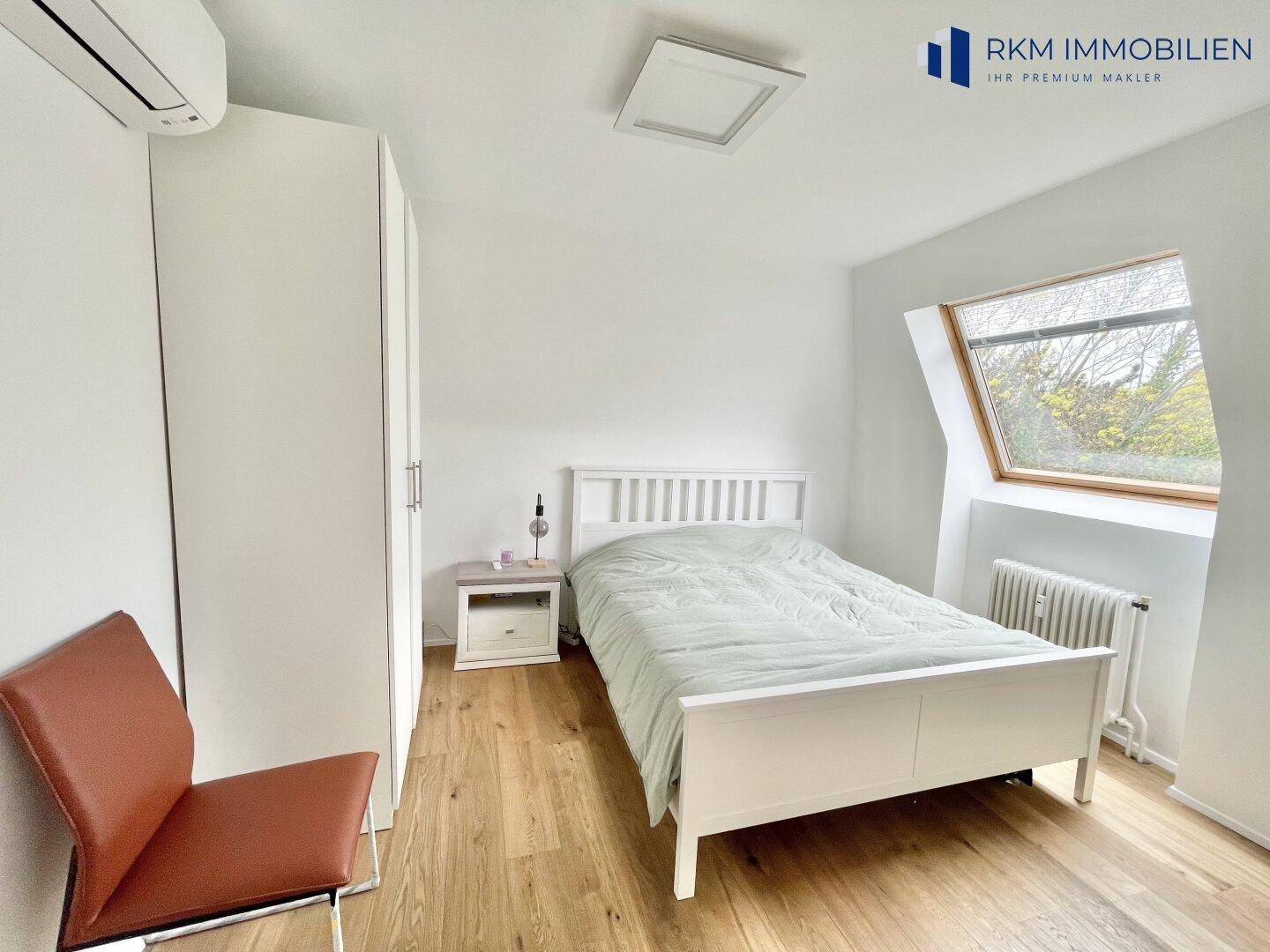 Gemütliches Schlafzimmer mit weißem Kleiderschrank, Holzboden und Dachfenster, inklusive Klimaanlage.