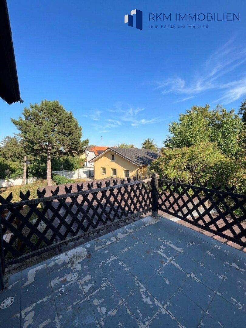 Balkon mit Holzgeländer und Blick auf die Nachbarschaft und Bäume.