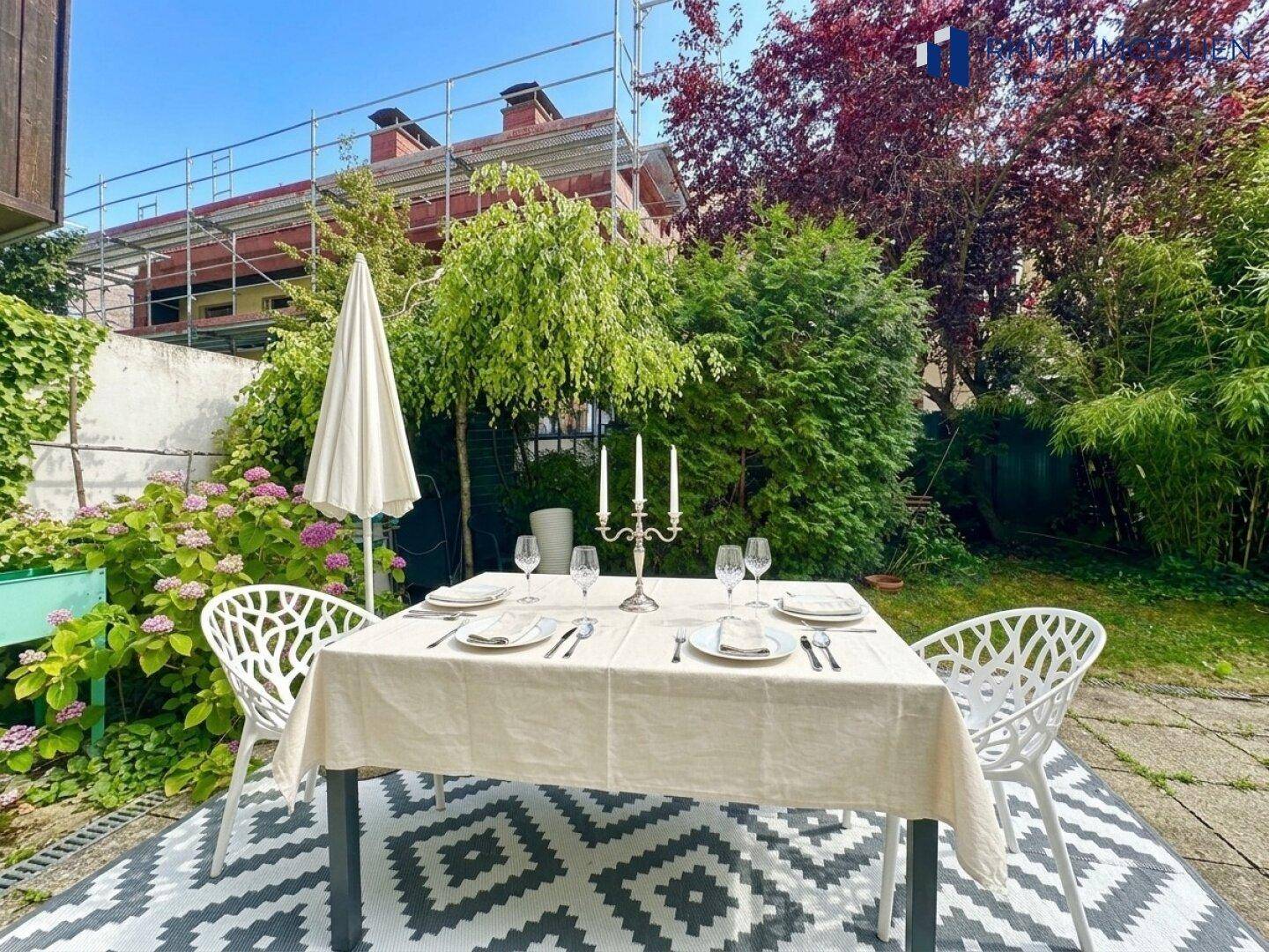 Gemütlicher Essbereich im Garten mit Tisch, Stühlen und umgebender Bepflanzung.