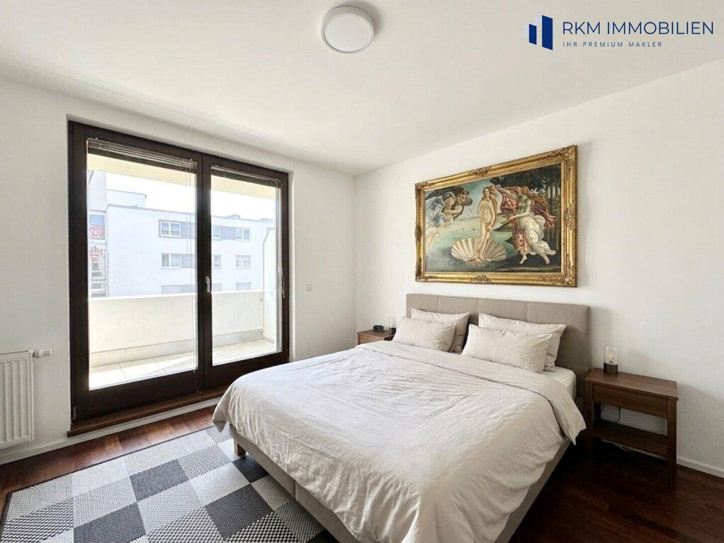 Schlafzimmer mit Holzboden, Doppelbett und direktem Zugang zum Balkon.
