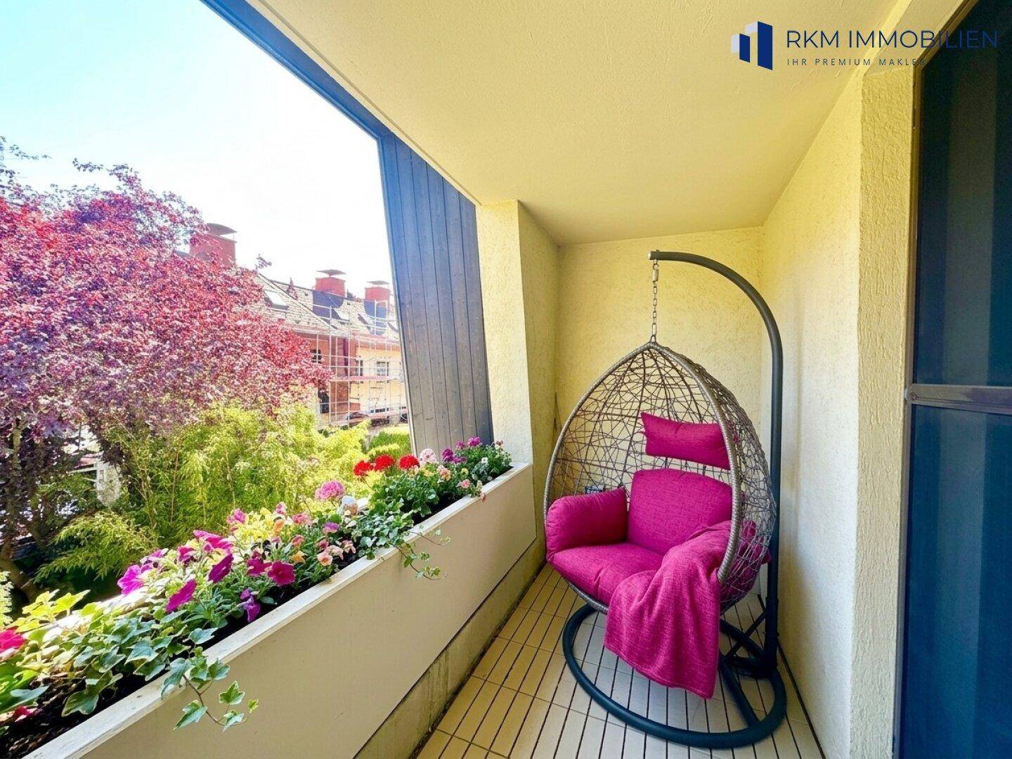 Gemütlicher Balkon mit Hängesessel, Blumenkästen und Blick ins Grüne.