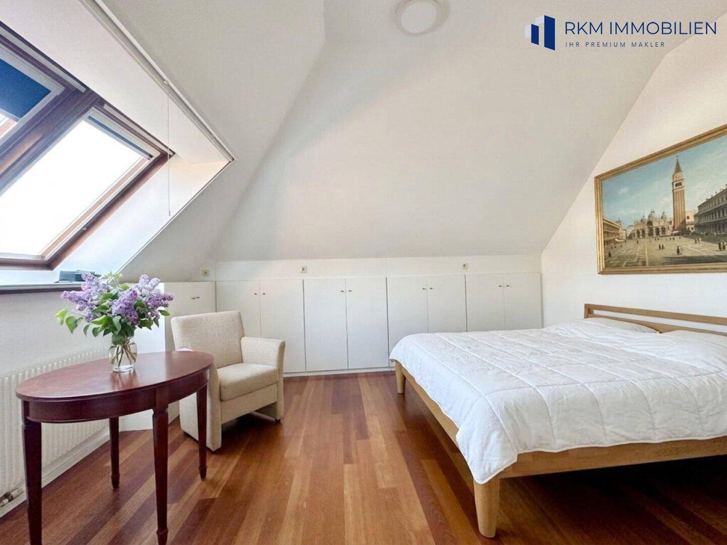 Helles Schlafzimmer im Dachgeschoss mit Holzboden, Dachfenster und Einbauschränken.