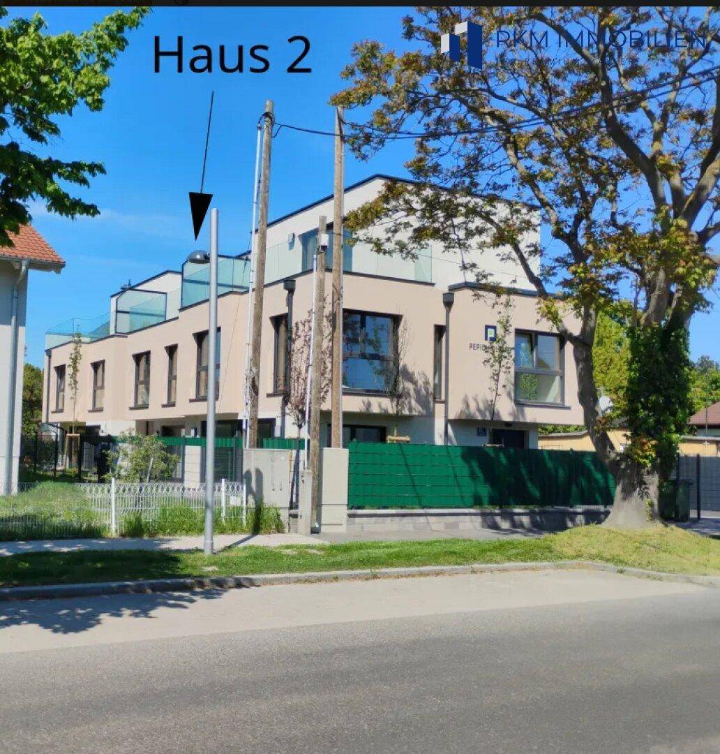 Ansicht der modernen Reihenhäuser von der Straße mit großzügigen Balkonen und Terrassen.