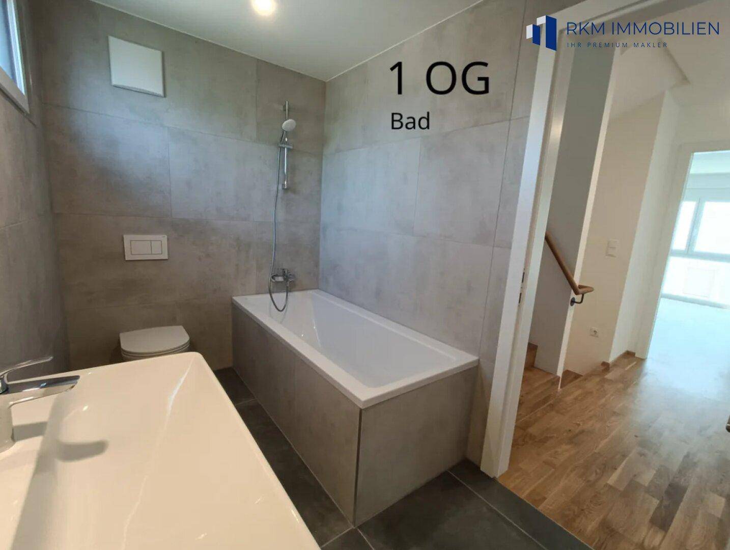 Modernes Badezimmer im ersten Obergeschoss mit Badewanne, WC und großformatigen Fliesen.
