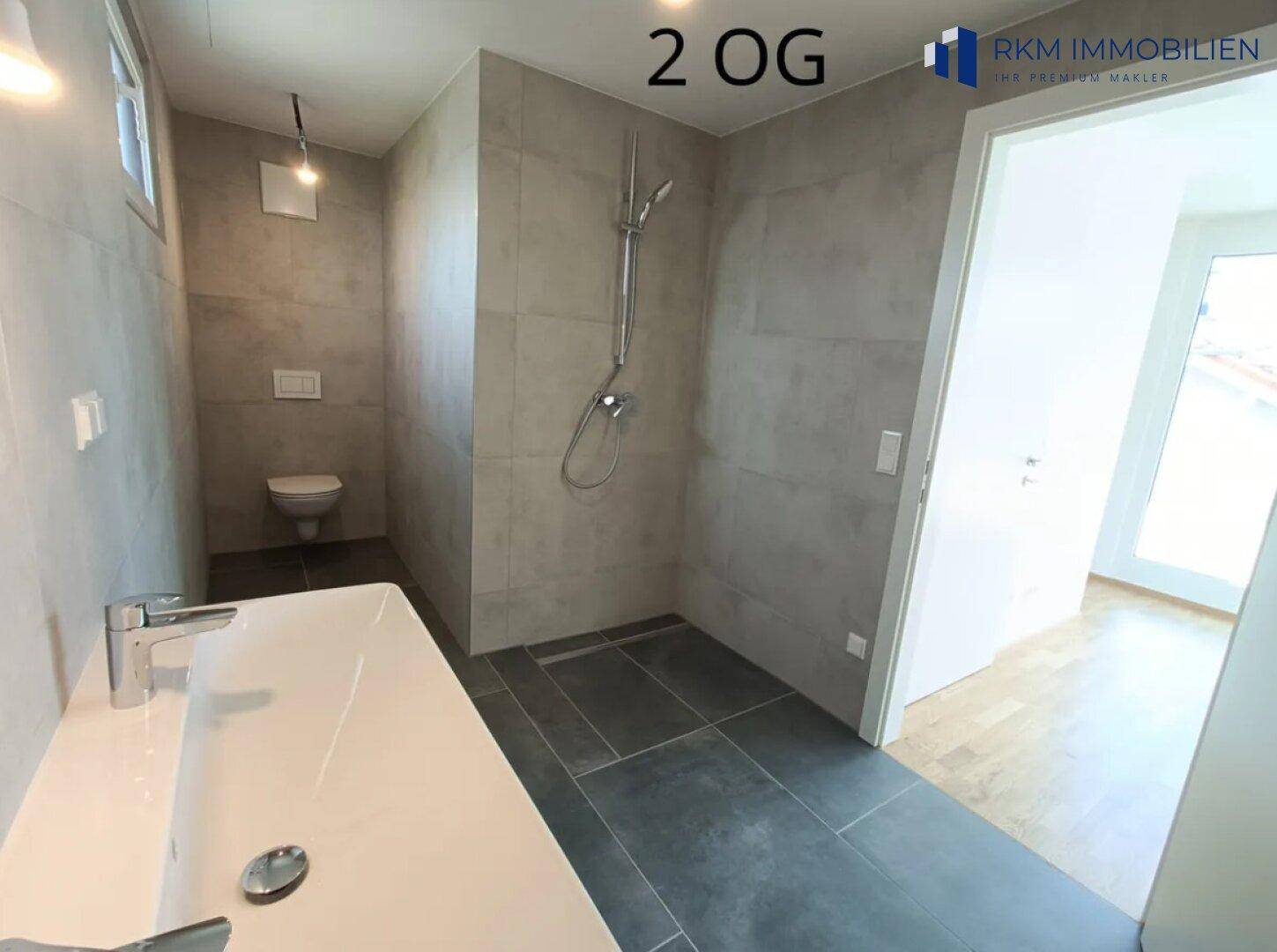 Modernes Badezimmer im zweiten Obergeschoss mit ebenerdiger Dusche, WC und Fenster.