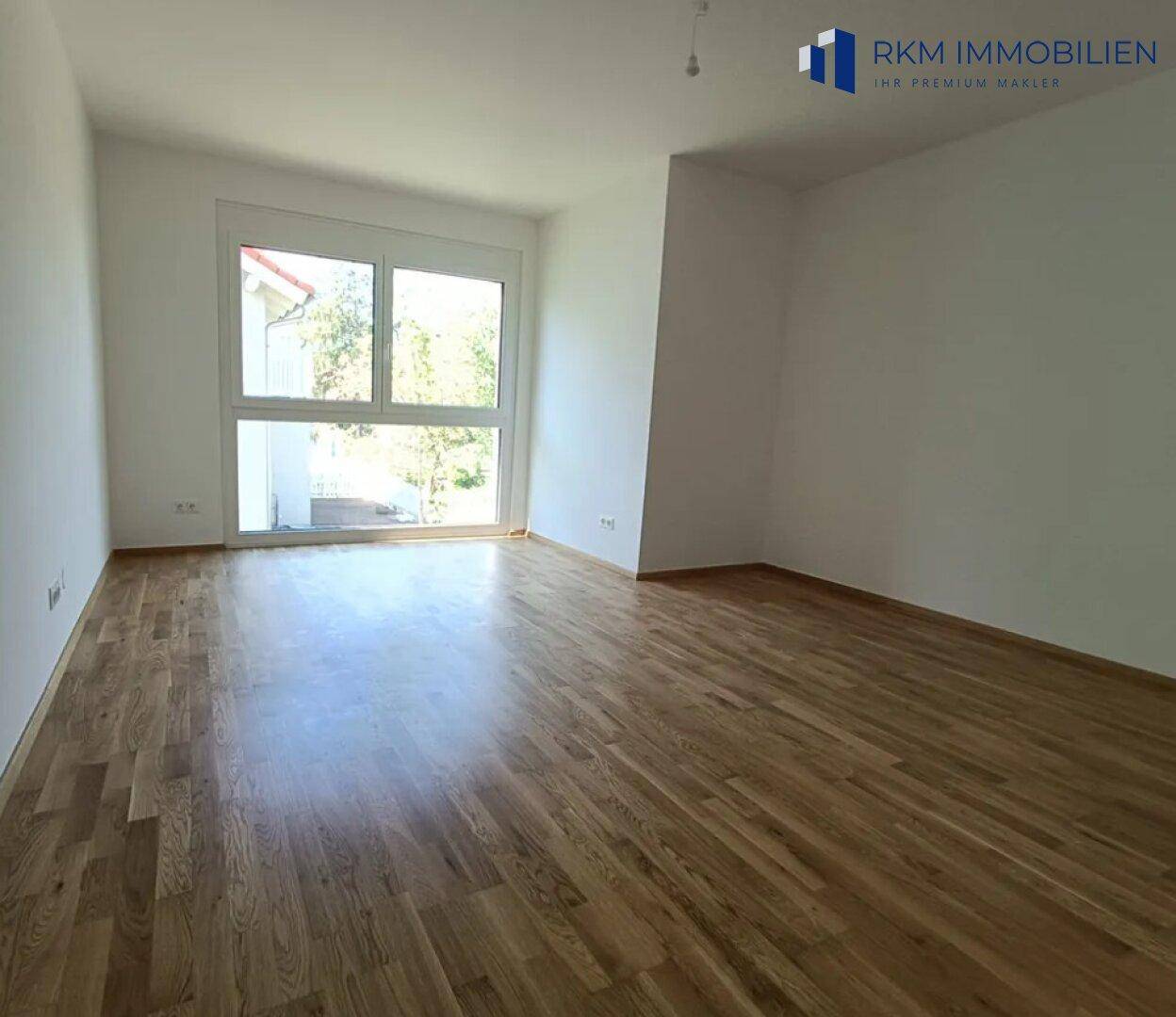 Freundliches Schlafzimmer mit Eichenparkett und weitem Blick durch die großen Fenster.