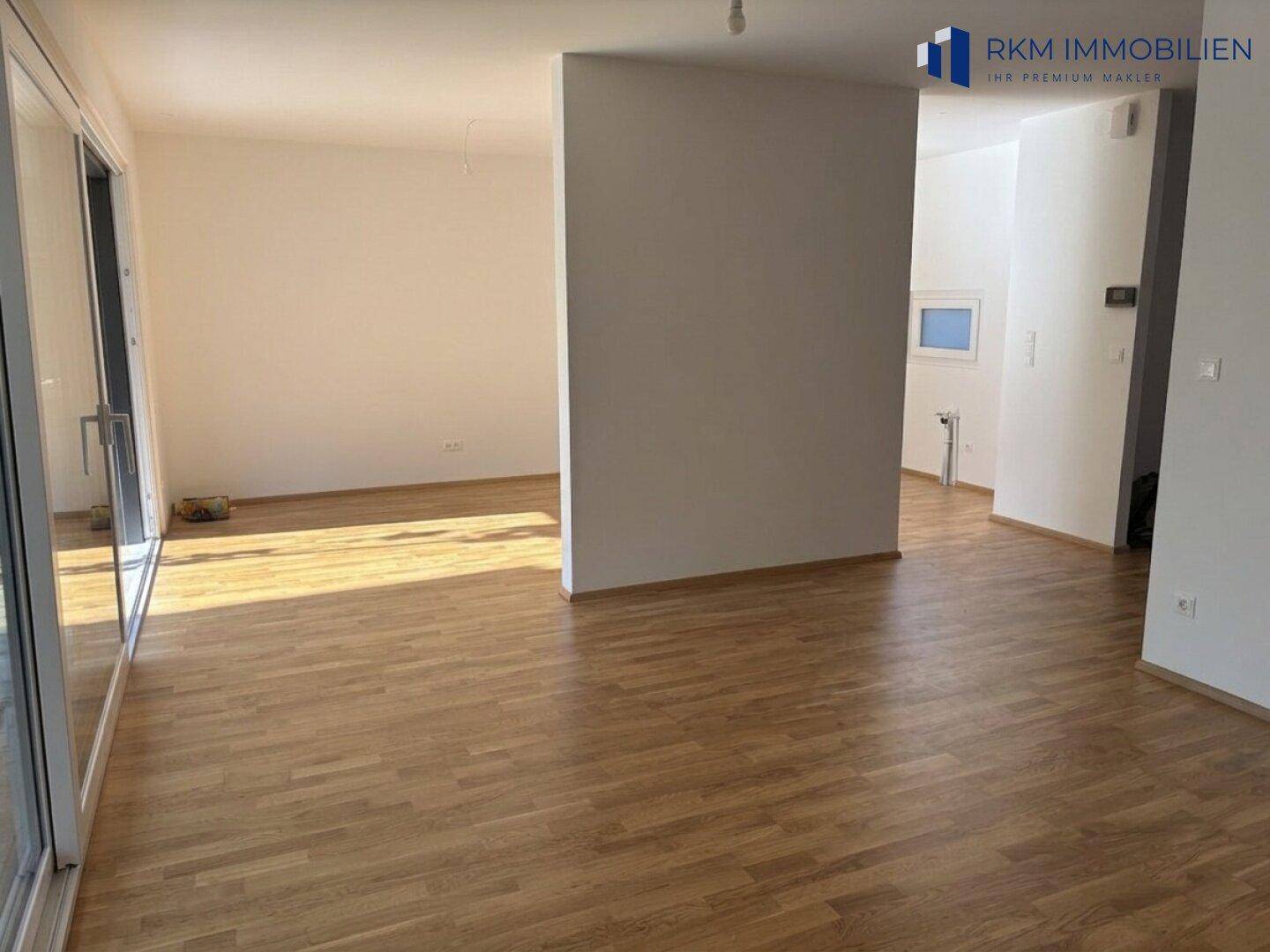 Geräumiger, offener Wohnbereich mit hellem Eichenparkett und Zugang zu den Außenbereichen.
