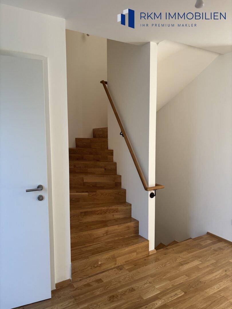 Moderne Holztreppe mit schlichtem Geländer, die die Stockwerke des Hauses verbindet.