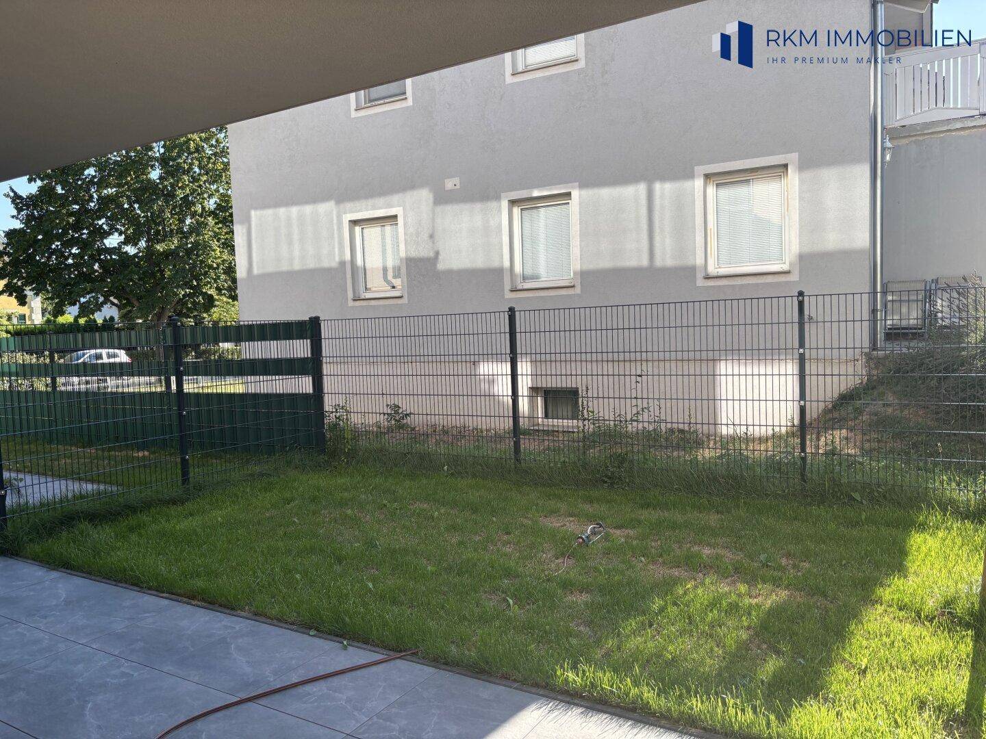 Kleiner privater Gartenbereich mit Rasenfläche und Zaun, ideal für Entspannung im Freien.