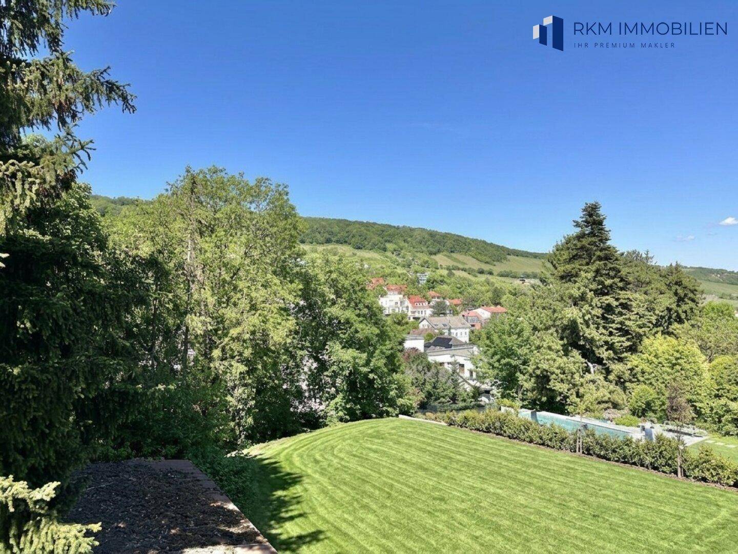 Gepflegter Rasenbereich mit weitem Blick auf die umliegende Landschaft und Häuser.