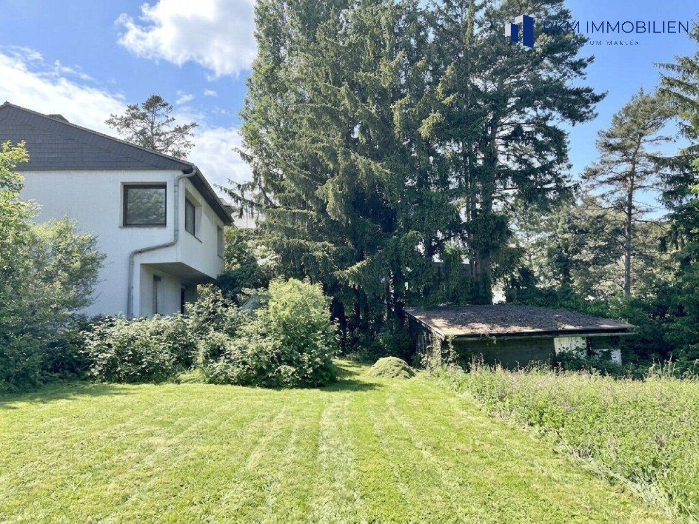 Großzügiger Gartenbereich mit Rasenfläche und altem Baumbestand neben dem Wohnhaus.