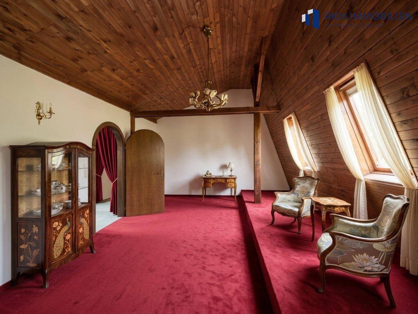 Geräumiges Wohnzimmer mit Holzbalkendecke, rotem Teppich und traditionellen Möbeln.
