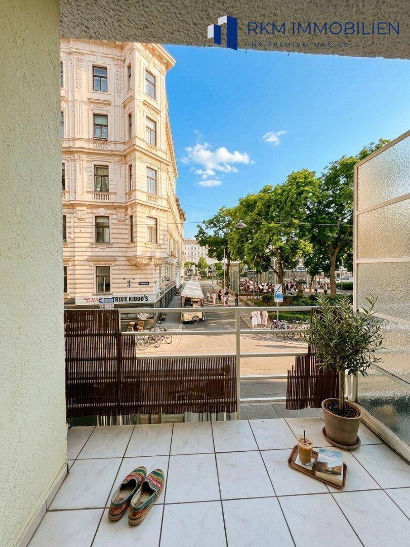 Kleiner Balkon mit Fliesenboden und Blick auf die belebte Stadtstraße.