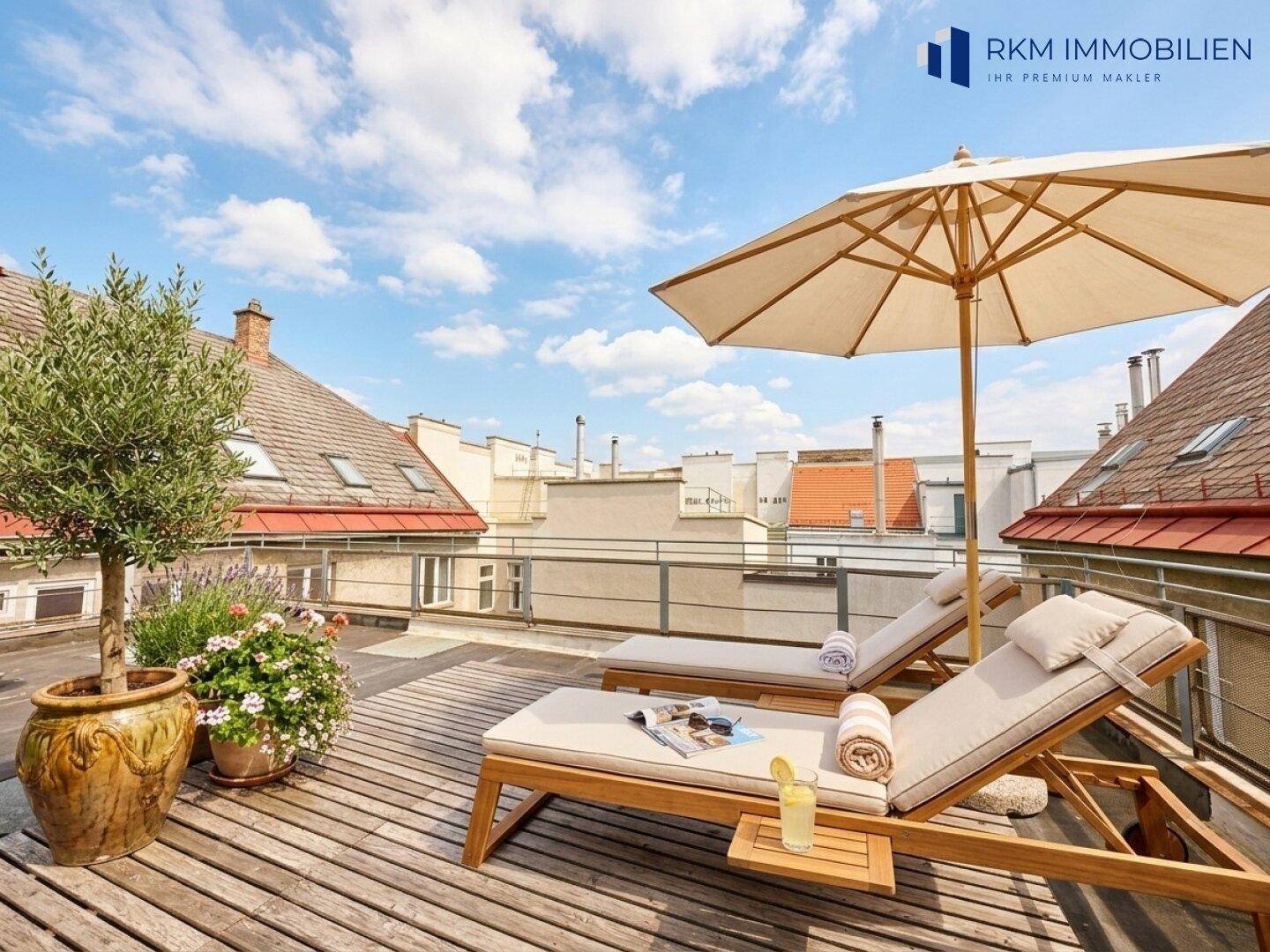 Geräumige Dachterrasse mit Holzdeck, Sonnenliegen und weitem Blick über die Dächer der Stadt.