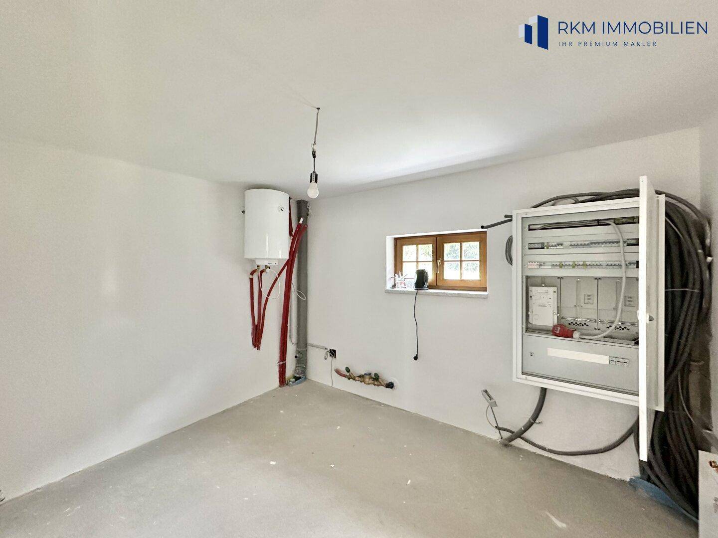 Technikraum mit Elektroverteilung und Warmwasserbereiter, bereit für die Installation der Haustechnik.