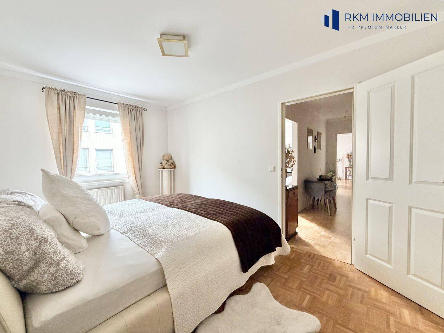 Gemütliches Schlafzimmer mit Parkettboden und Zugang zu einem weiteren Raum.