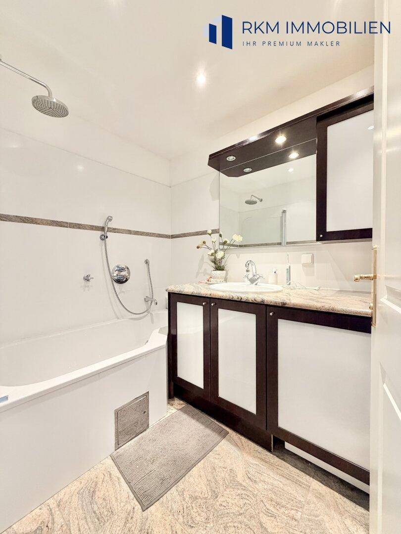 Modernes Badezimmer mit Badewanne, Dusche und Marmorwaschtisch.