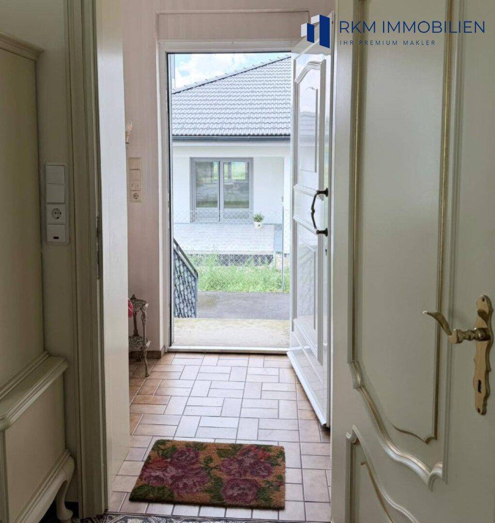 Eingangsbereich mit offener Tür, die den Blick auf die Außenseite des Hauses freigibt.