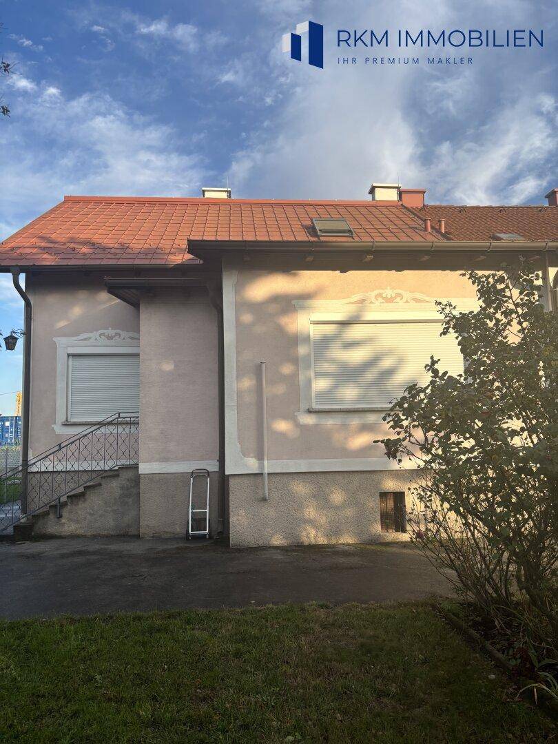 Seitenansicht des Hauses mit Rollläden an den Fenstern und einem Zugang zum Gartenbereich.