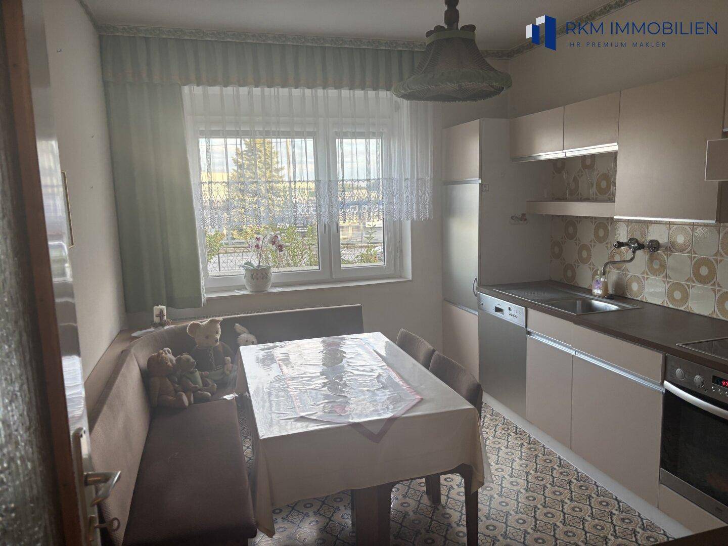 Funktionale Küche mit Einbaumöbeln, Essbereich und einem Fenster, das viel Licht hereinlässt.