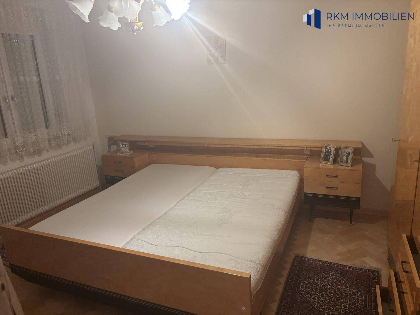Schlafzimmer mit Doppelbett, Nachttischen und einem Teppich, das eine gemütliche Atmosphäre schafft.