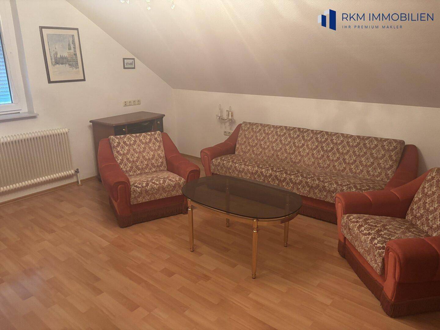 Gemütliches Dachzimmer mit Sitzgruppe, Couchtisch und schrägen Wänden, ideal als zusätzlicher Wohnraum.
